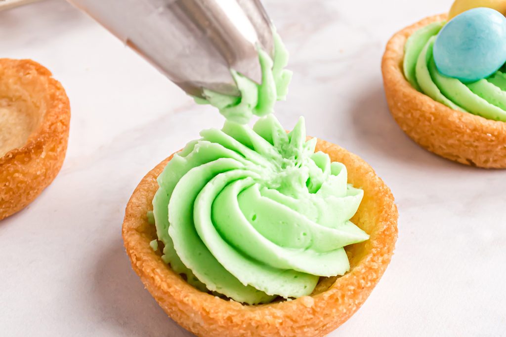green frosting piped into sugar cookie cup
