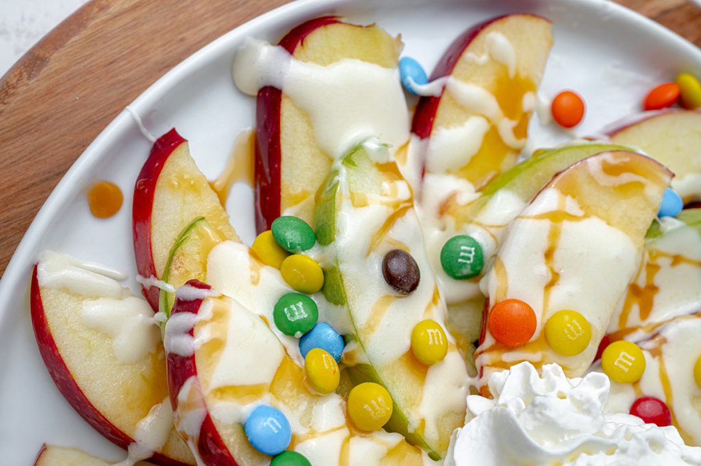 close up of apple nachos with m&ms , caramel and marshmallow