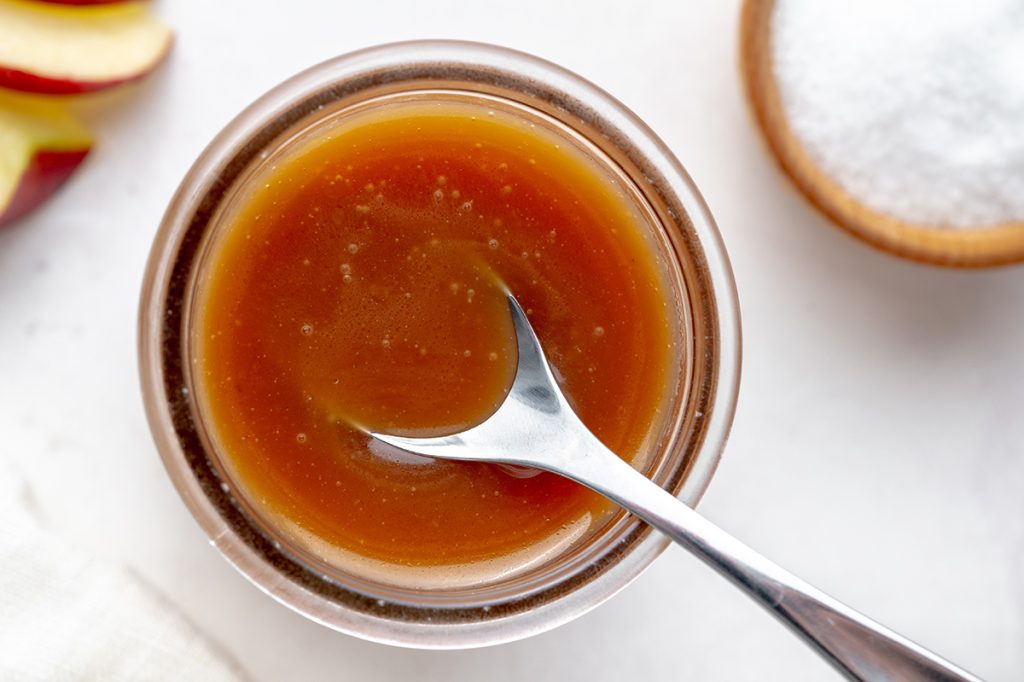 spoon in caramel in a glass jar