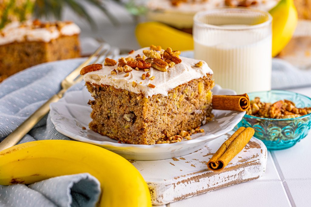 slice of hummingbird cake on a white plate with cinnamon stick