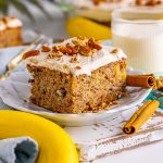 slice of hummingbird cake on a white plate with cinnamon stick