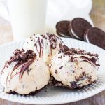 three mini oreo cheesecakes on a plate with oreos in the background