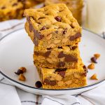 stack of cookie bars with peanut butter and chocolate chips on a white plate