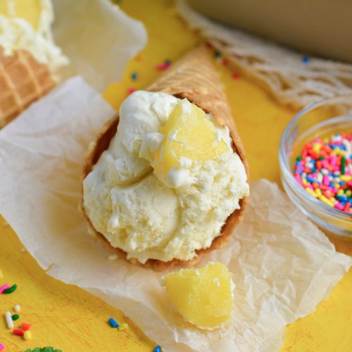 close up of pineapple ice cream cone laying on parchment paper