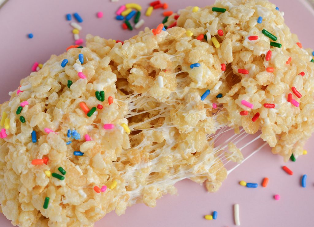 close up of torn apart rice krispie treat with sprinkles on a pink plate