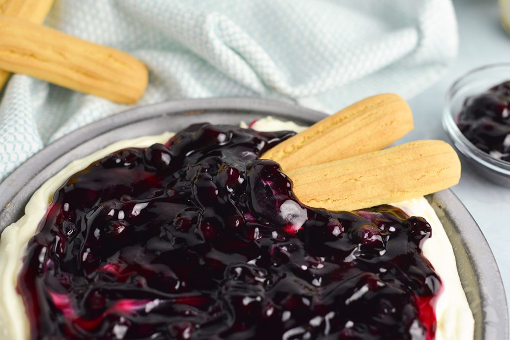 two lady fingers in blueberry cheesecake dip