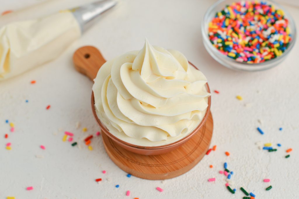 buttercream frosting in a bowl with sprinkles in the background