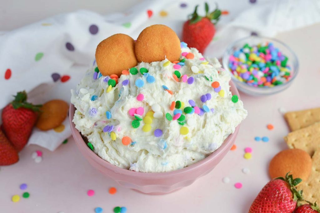 funfetti dip in a pink bowl with vanilla wafers and sprinkles