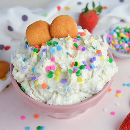 funfetti dip in a pink bowl with vanilla wafers and sprinkles