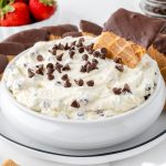 bowl of cannoli dip with chocolate chips and a waffle cone dipper
