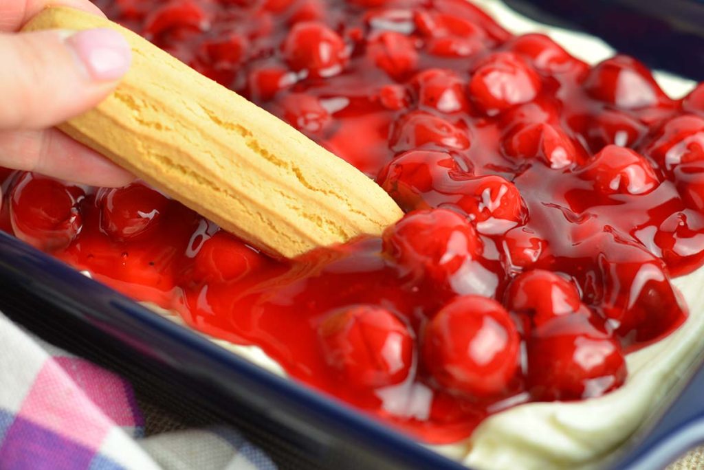 lady finger dipping into cherry cheesecake dip