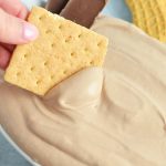 graham cracker dipping into chocolate cheesecake dip