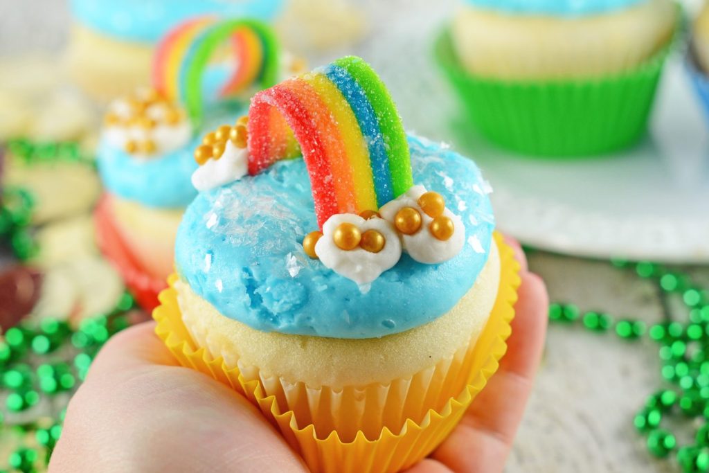hand holding one rainbow cupcake