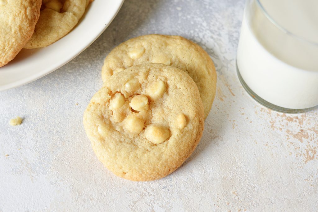 overhead shot of two white chocolate chip cookies with a glass of milk