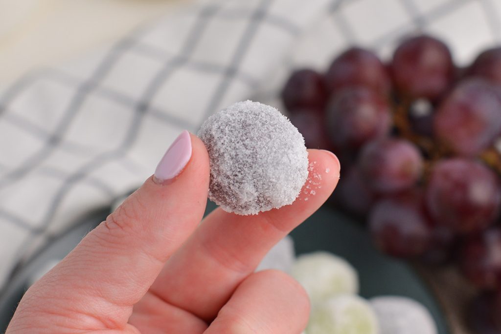 fingers holding one frosted grape