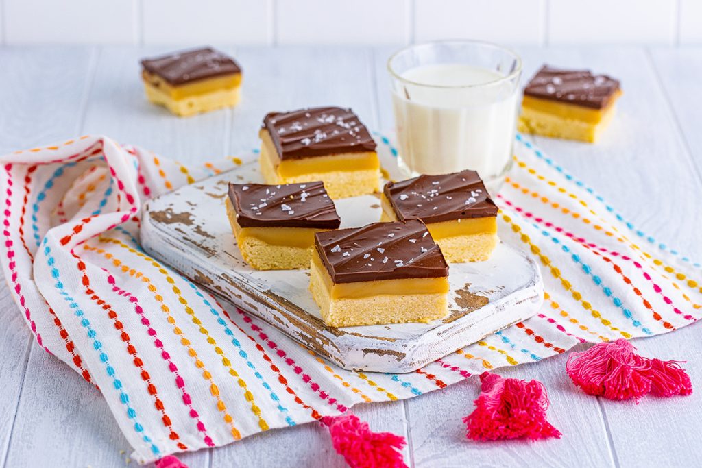 millionaire bars on a tray with a glass of milk