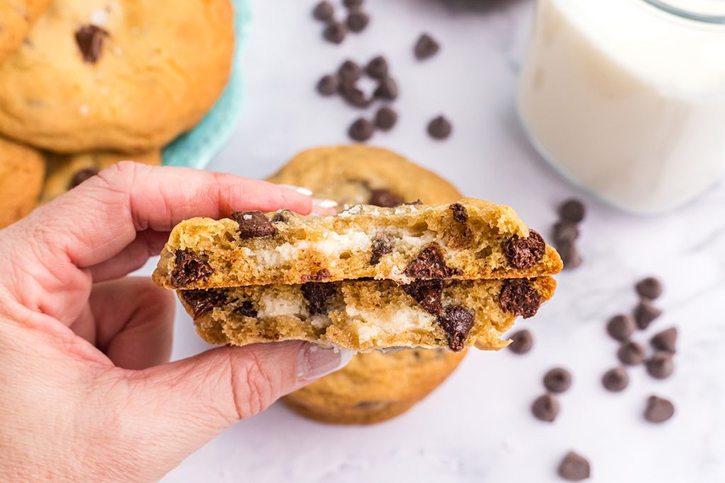 hand holding two halves of cream cheese stuffed chocolate chip cookies