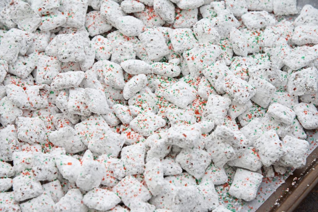 angled shot of christmas puppy chow on baking sheet