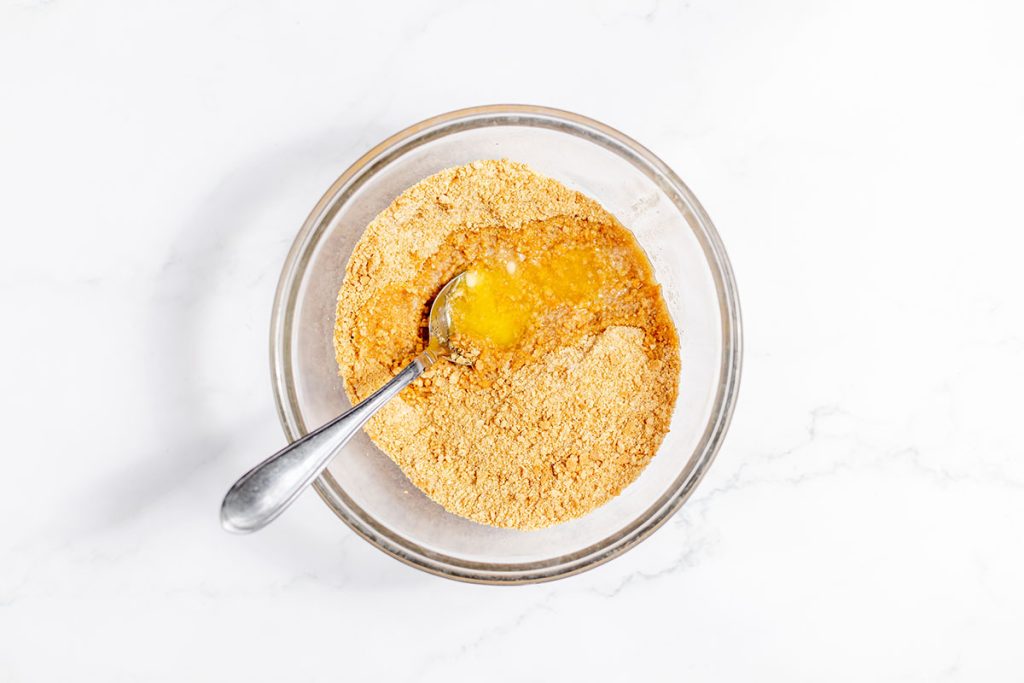 melted butter added to graham crackers in a bowl