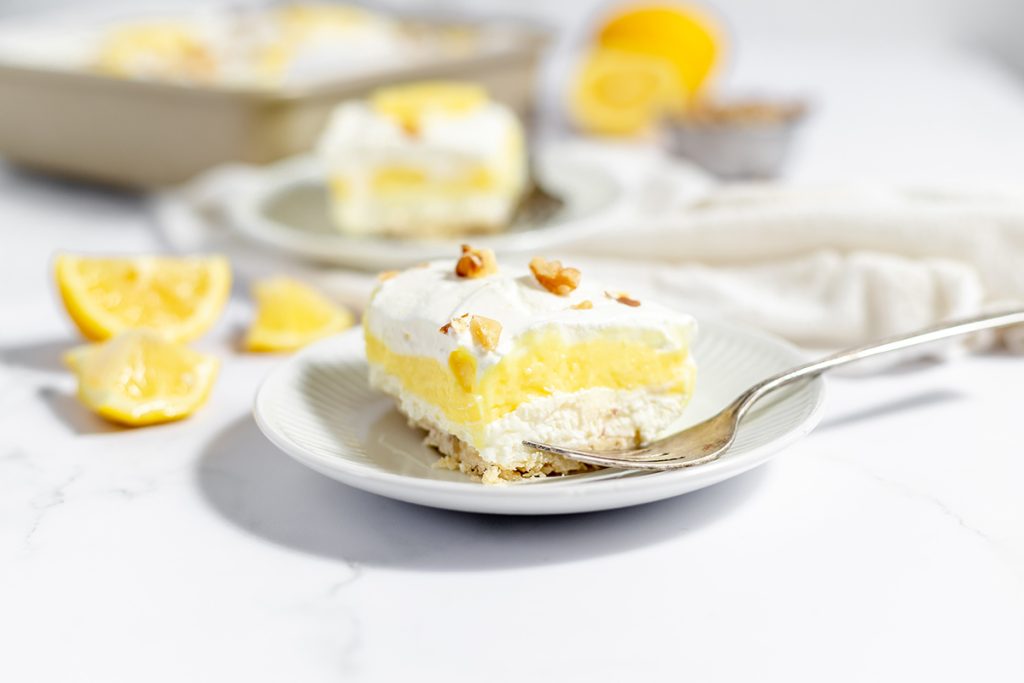 straight on shot of layered lemon dessert on plate with fork