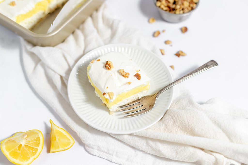 angled shot of slice of lemon dessert on plate with fork