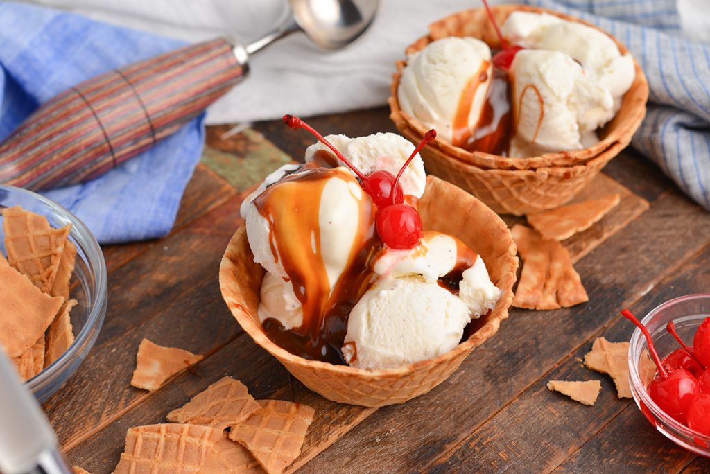 angled shot of two butterscotch sundaes topped with cherries