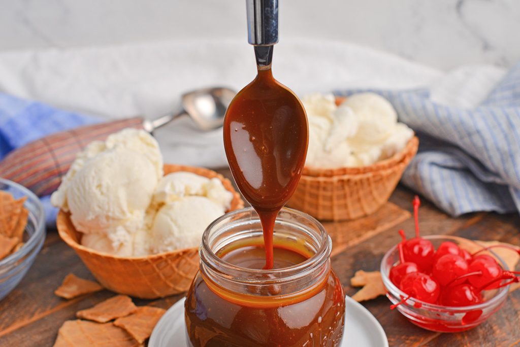 spoon dipping into jar of butterscotch sauce