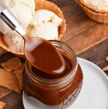angled shot of spoon dipping into jar of butterscotch sauce
