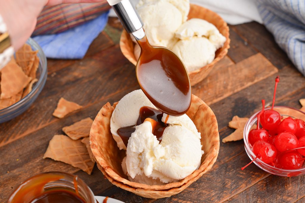 spoon drizzling dessert sauce onto ice cream