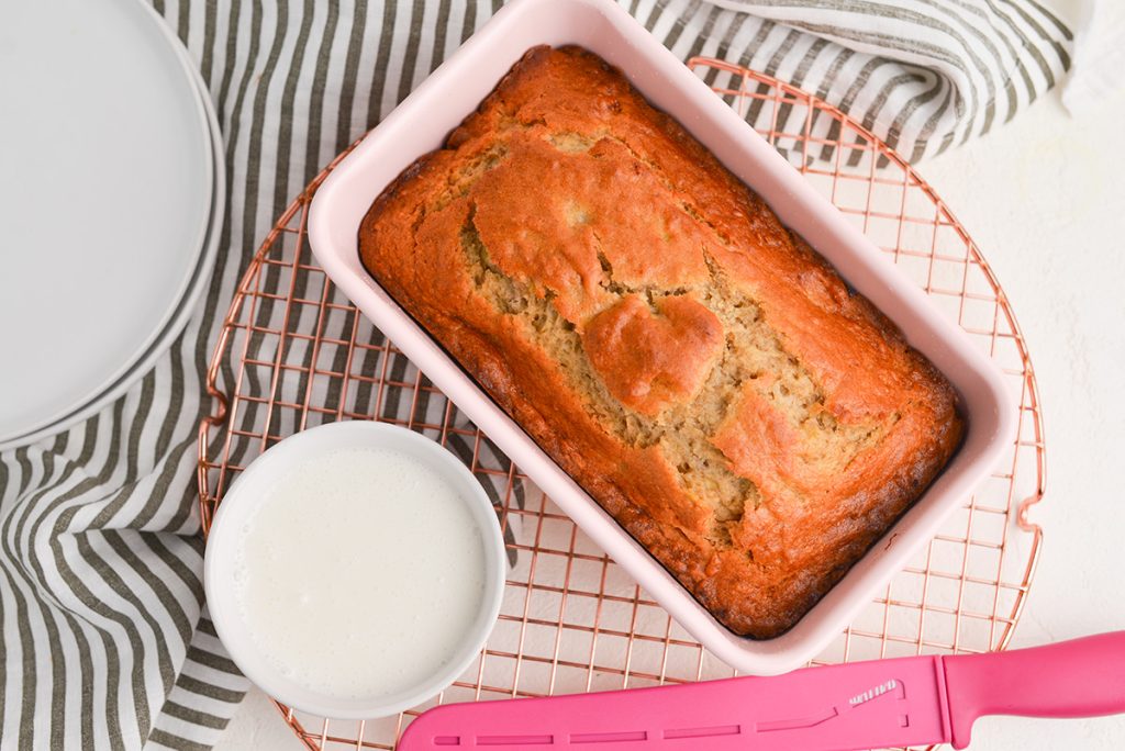 overhead shot of bowl of icing and loaf of banana bread