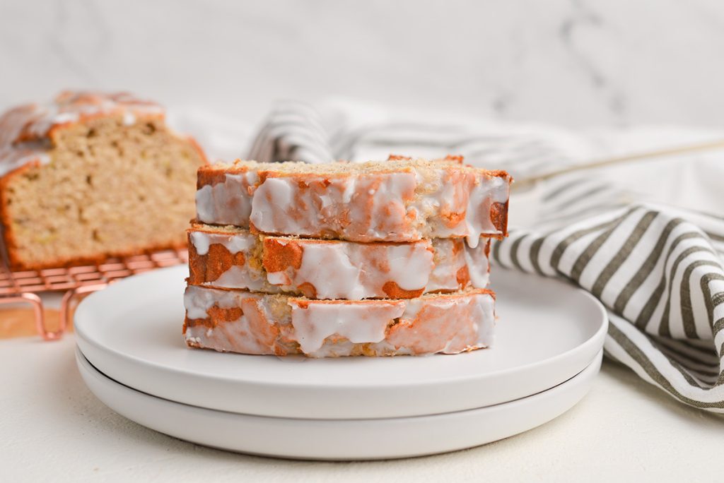 straight on shot of three slices of iced banana bread loaf on a plate