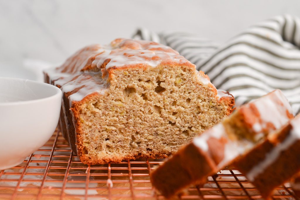 straight on shot of banana bread with icing on a cooling rack