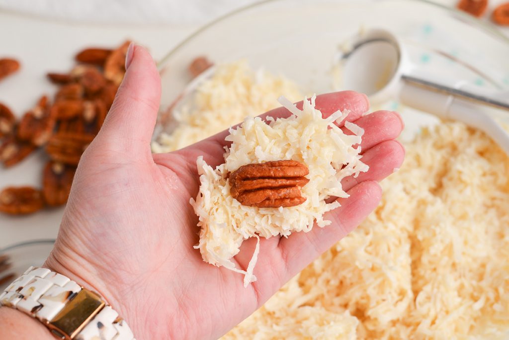 hand holding coconut mixture topped with a pecan